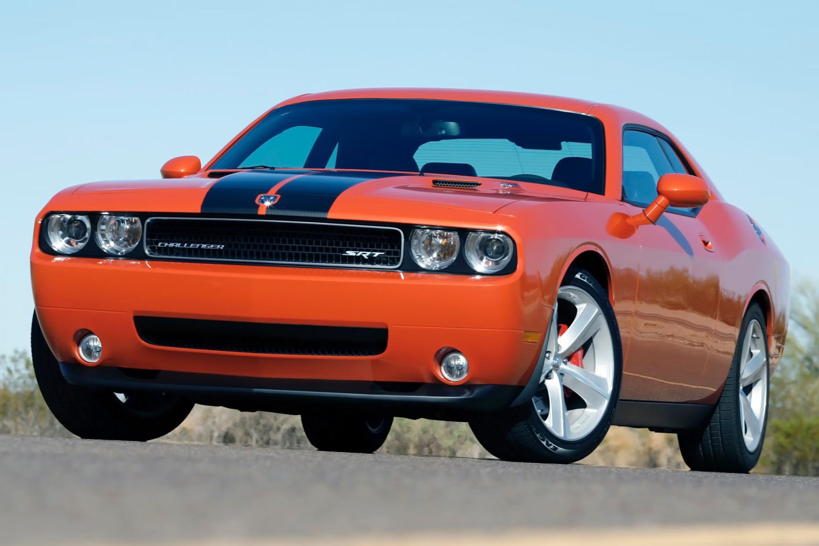An orange challenger driving on the road.
