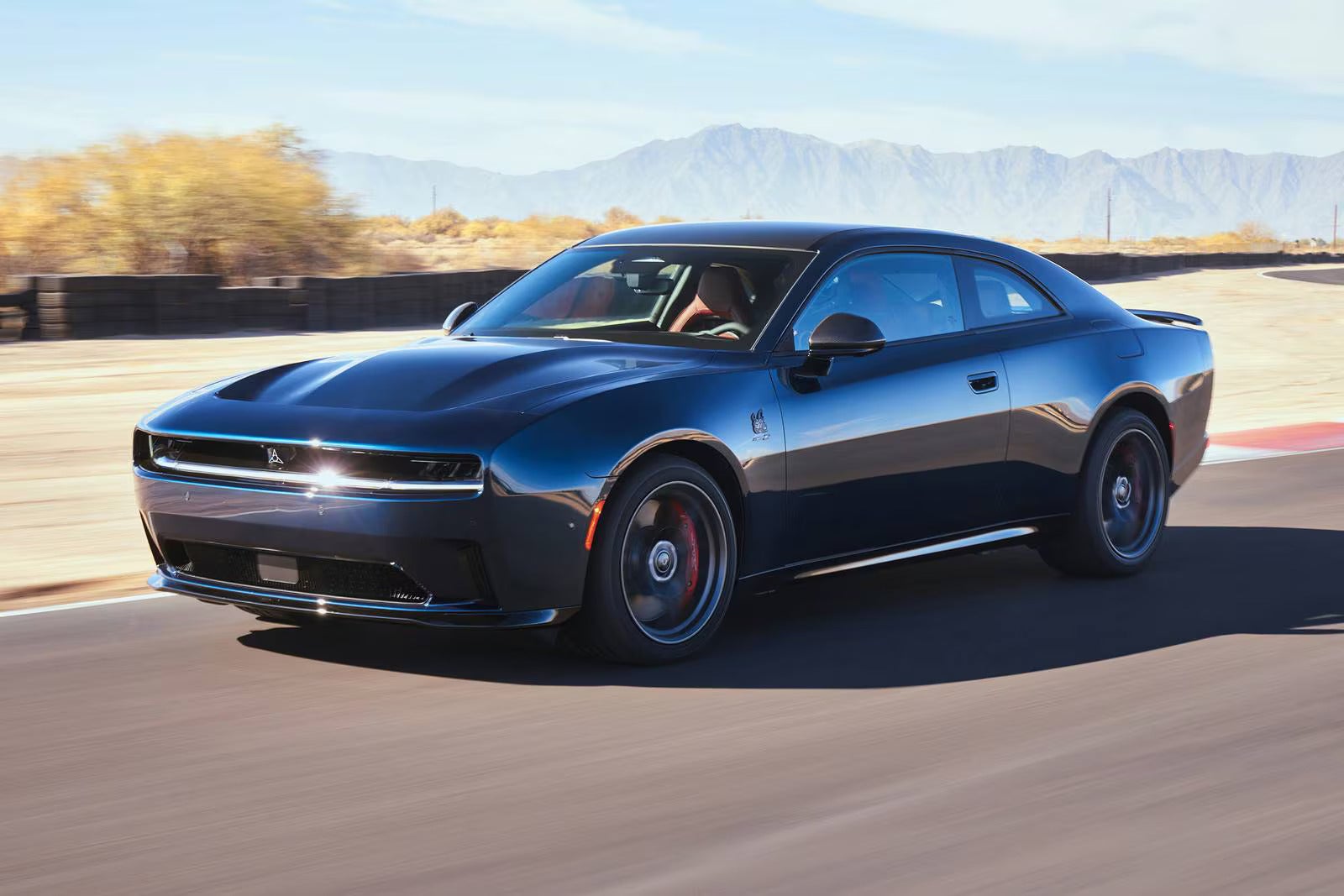 A blue charger driving on a track.