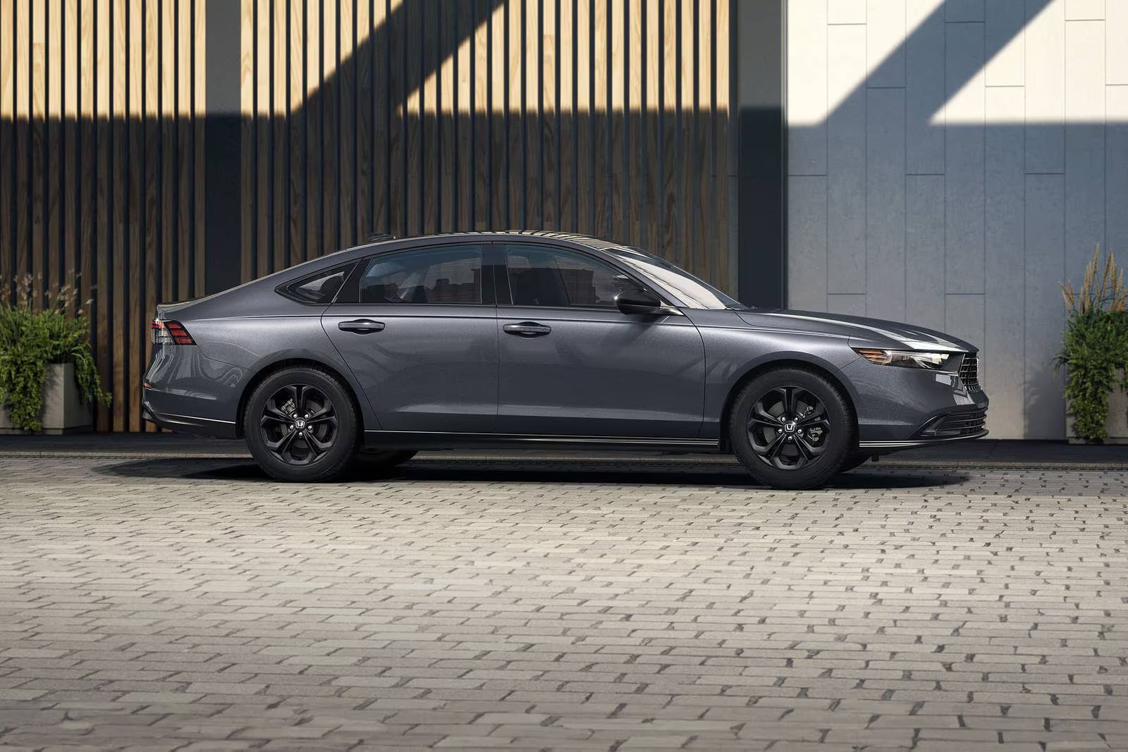 A gray car sitting parked on the side of the road.