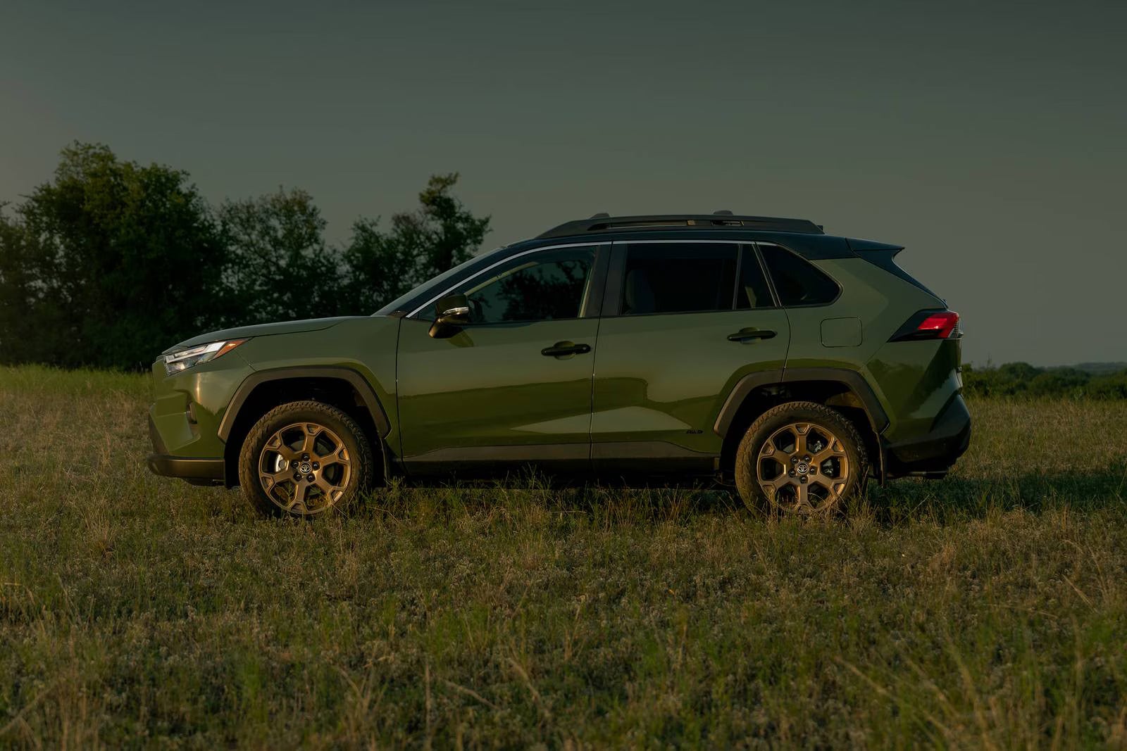A green suv sitting parked in a field.