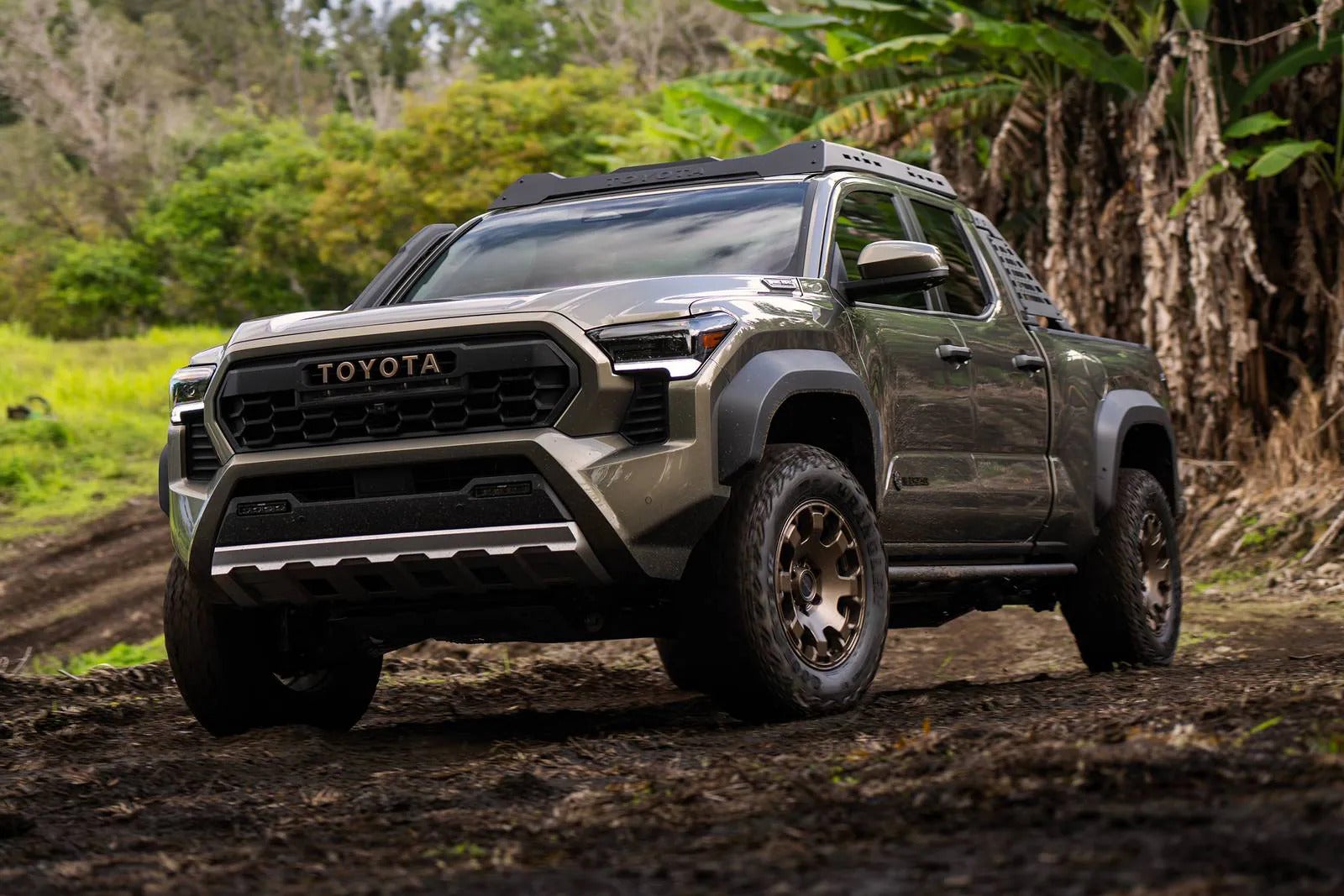 A green toyota truck sitting parked in the dirt.