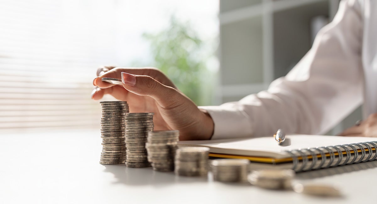 a person counting quarters stacked up on a desk