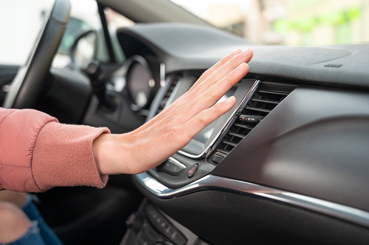 a woman holding her hand next to a a/c vent in a vehicle