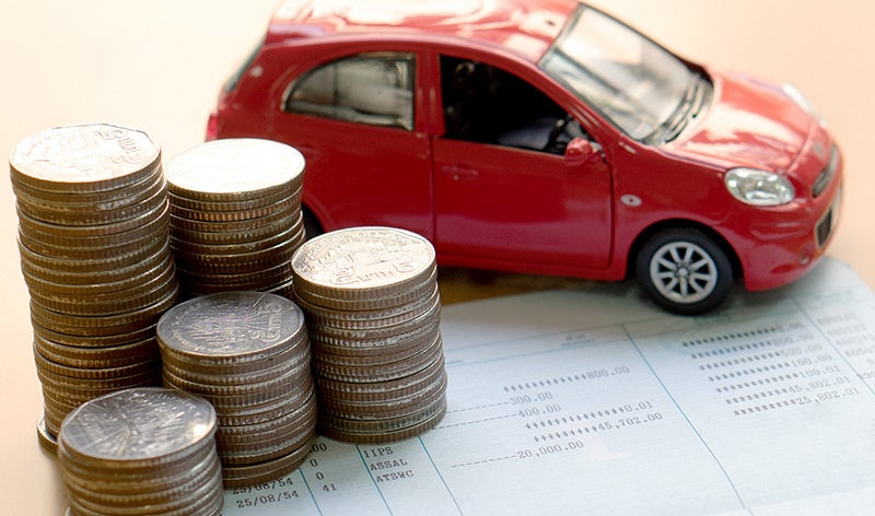 stacks of quarters next to a small red car