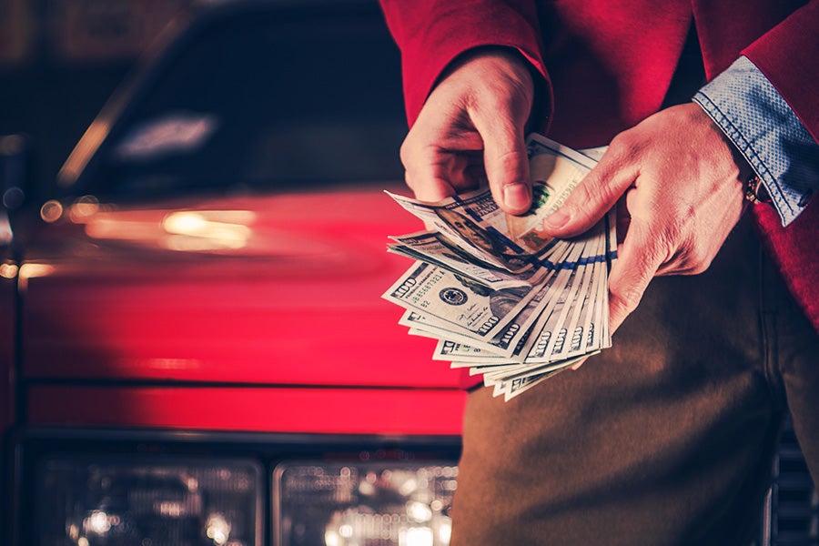 a person holding cash next to a vehicle